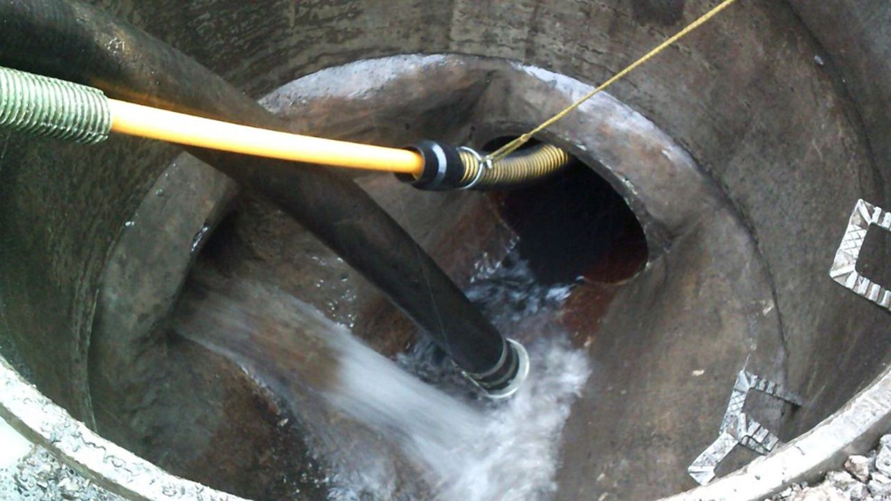 Removing silt with a jet vacuumation pipe from within a sewer, while water runs into the sewer from another pipe