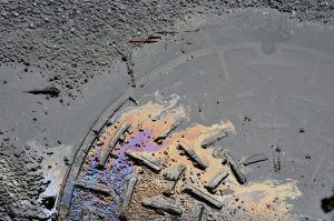 Oil spill on a manhole cover on an asphalt road