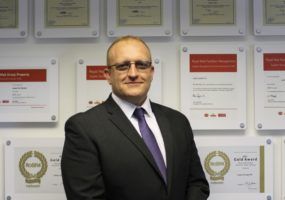 Chris Wilde of Lanes Group standing in front of accreditations
